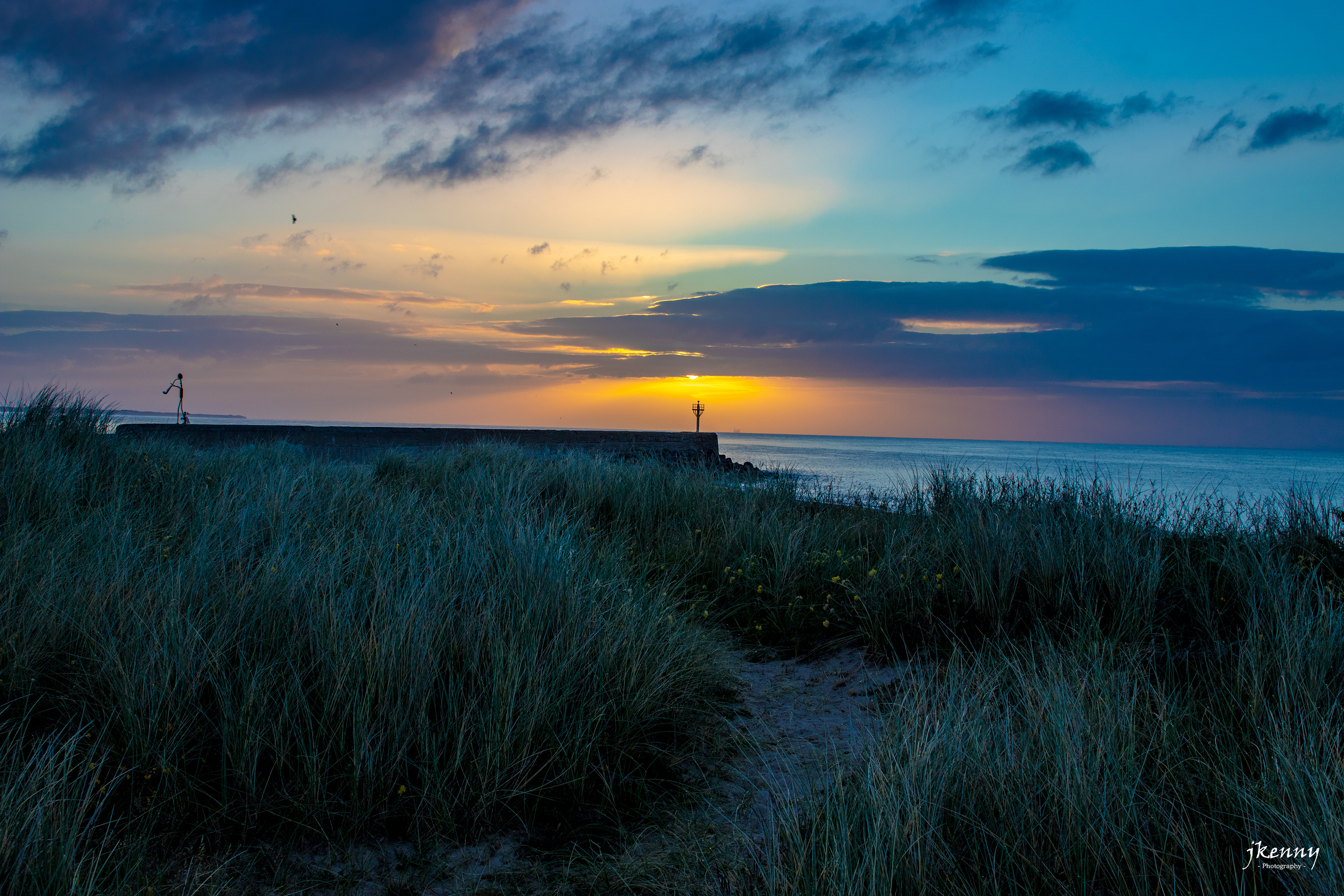 Arklow South Pier with the sun behind it.